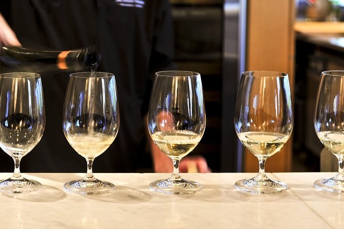 Five glasses of white poured along a counter for a tasting