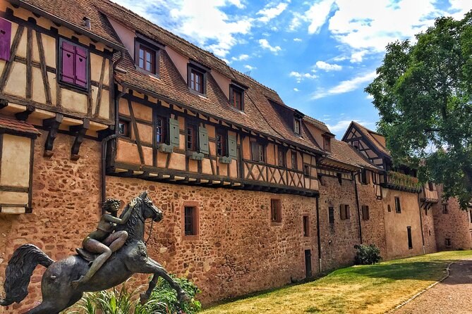 A long stone town wall under a tiled roof, a rearing bronze horse at its foot